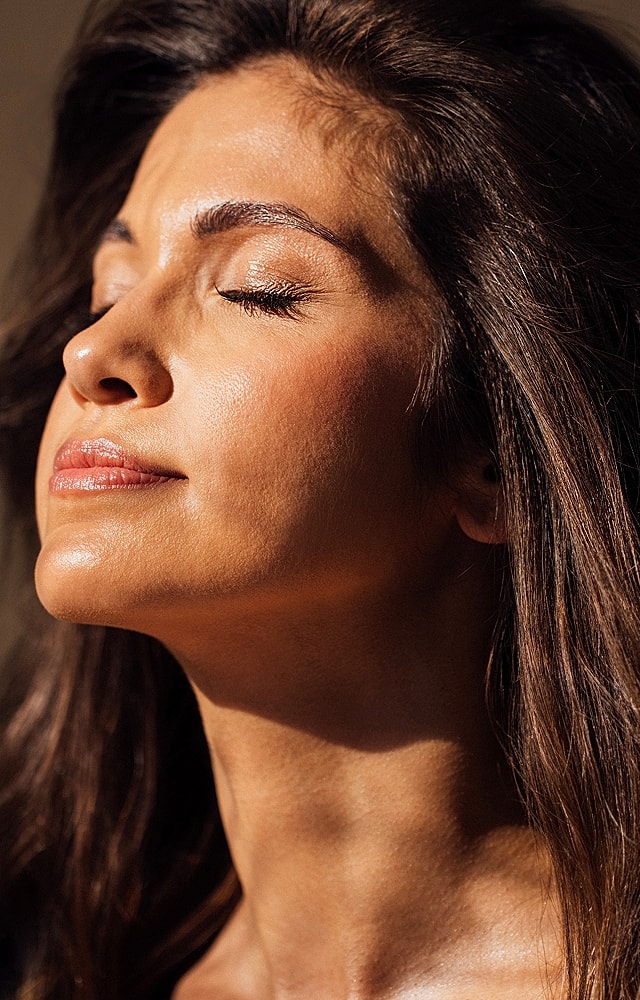 Woman enjoying sunlight, eyes closed blissfully.